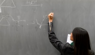 student writing on chalkboard
